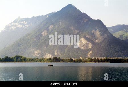 Einsames Boot auf dem Alpensee mit majestätischem Schweizer Gipfel - Schweiz der 1990er Jahre Stockfoto