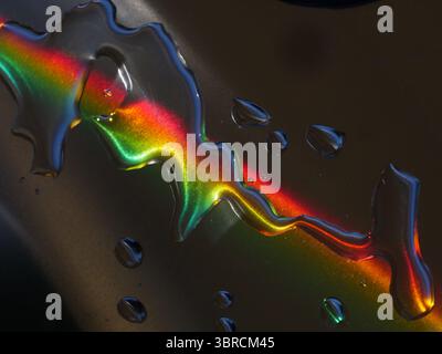 Regenbogen wird in den Wassertropfen auf einer Oberfläche reflektiert Stockfoto