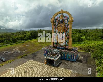 Aus der Vogelperspektive auf die majestätische goldene Statue, die vor der üppigen grünen Kulisse und dem bewölkten Himmel glänzt, Quatre Bornes, Plaines Wilhems District, Mauritius. Stockfoto