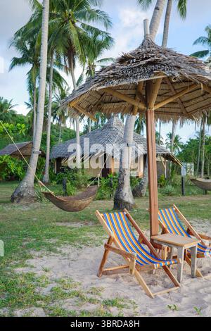 Wunderschöne tropische Liegestühle und Strohschirme am Meer in El Nido, Palawan, Philippinen. Weiche Wolken und romantische Atmosphäre Stockfoto