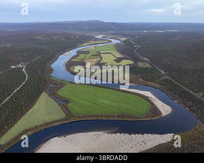 Aus der Vogelperspektive auf den sich windenden Fluss, der den Himmel reflektiert, durch grüne Felder und Sandbänke, unter einem riesigen Himmel, Karasjok, Finnmark, Norwegen. Stockfoto