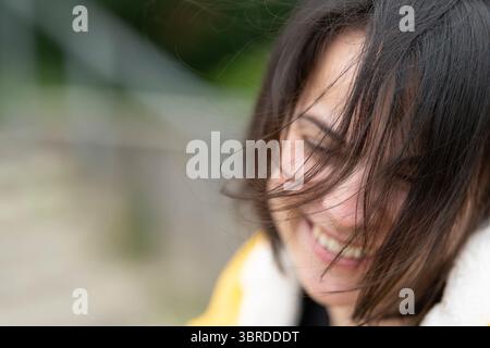 Nahaufnahme einer lächelnden Frau in gelbem Regenmantel umgeben von Natur. Konzept: Fröhliche Einfachheit, frische Energie, natürliche Schönheit, Outdoor-Glück. Stockfoto