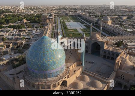 Majestätisch erhebt sich der Blick aus der Vogelperspektive auf die leuchtende türkisfarbene Kuppel der Shah-Moschee und kontrastiert mit den gedämpften Erdtönen der umliegenden Stadt Isfahan, Provinz Isfahan, Iran. Stockfoto