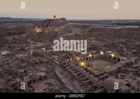 Aus der Vogelperspektive der alten Arg-e BAM Zitadelle, die warm vor dem kühlen Abendhimmel leuchtet, ein Zeugnis für Geschichte und Widerstandsfähigkeit, BAM, Provinz Kerman, Iran. Stockfoto