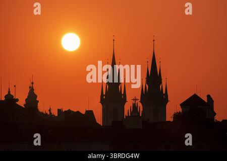 Aus der Vogelperspektive auf gotische Türme und Dächer, die sich vor einem feurigen, orangen Himmel bei Sonnenaufgang in Prag, Tschechien, abzeichnen. Stockfoto
