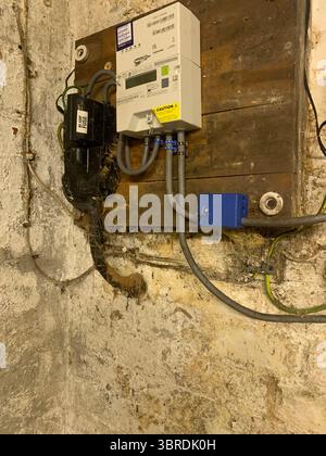 Alte elektrische Verkabelung Haupteinheit Gasbox Rohre Drähte Kabel schmutzig schmuddelig an der Wand in einem Keller Meter Gas Elektrizität Holzrahmen Elektrik UK Stockfoto