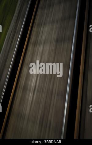 Dynamische Aufnahme von Eisenbahngleisen in Bewegung mit verschwommenem Effekt, Blick vom fahrenden Zug auf die Gleise. Bahngleise in Deutschland Stockfoto
