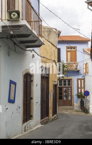 Blick auf sonnendurchflutete Gebäude mit verwitterten Steinmauern und Holzläden säumen eine enge Straße und schaffen eine bezaubernde Szene, Pano Lefkara, Larnaca, Zypern. Stockfoto
