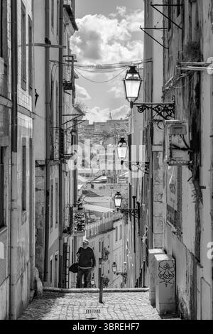Enge Kopfsteinpflasterstraße mit traditionellen bunten Gebäuden und historischen Straßenlaternen im Lissabonner Stadtteil Bairro Alto. Stockfoto