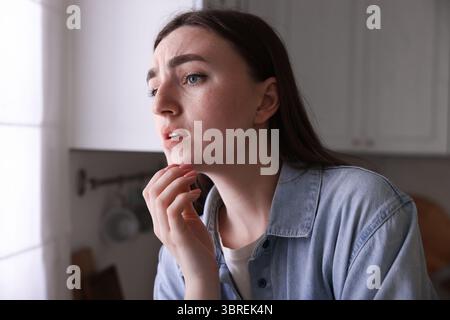 Besorgte Frau, die in der Küche an Paranoia leidet Stockfoto