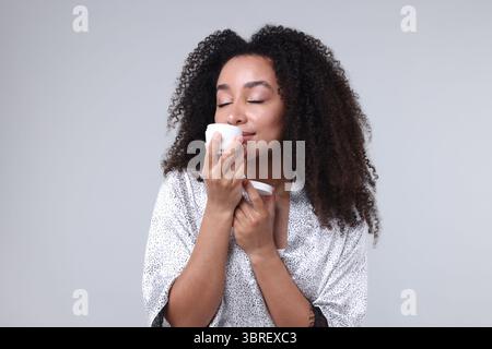 Schöne brasilianische Frau mit einem Glas Kollagencreme auf grauem Hintergrund Stockfoto