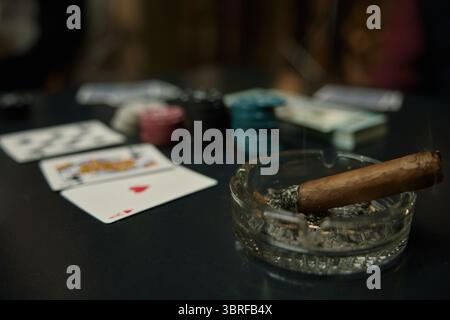 Eine ruhige Pokerszene mit einer erloschenen Zigarette, bunten Chips und Spielkarten Stockfoto