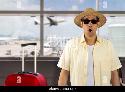 Mann im Urlaub mit gelbem Hemd Hut Sonnenbrille am Flughafen Angst und schockiert mit überraschendem Ausdruck, Angst und aufgeregtem Gesicht. Stockfoto