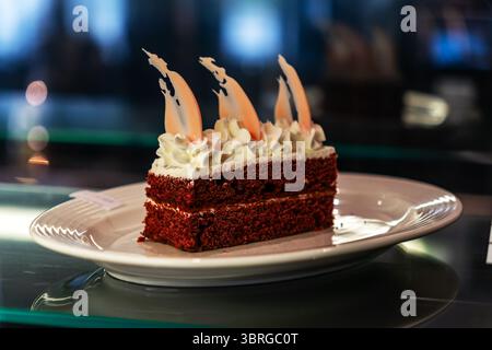Schokoladenbrownie quadratische Stücke im Stapel auf weißem Teller dekoriert. Schokoladenkuchen oder ein Stück Kuchen mit weißer Creme auf einem weißen Teller. Amerikanischer Tradi Stockfoto