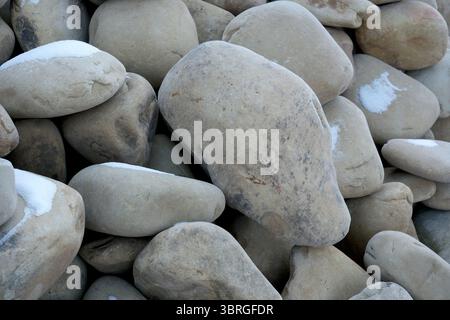 Glatte, mit Schnee bestaubte Steine schaffen eine ruhige Winterszene. Stockfoto