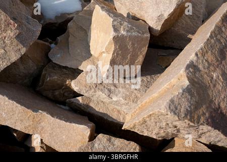 Sonnenlicht hebt die einzigartigen Texturen verwitterter Steine auf einem Stapel hervor. Stockfoto