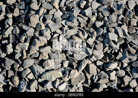 Eine Nahaufnahme verschiedener grauer Kiessteine, die über den Boden verstreut sind. Stockfoto