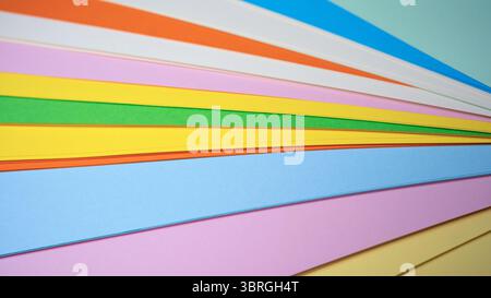 Bunte Papierbögen überlappen sich, was einen fröhlichen Regenbogeneffekt erzeugt. Stockfoto
