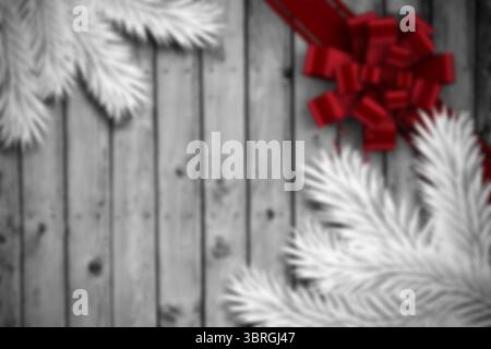 Rote Schleife glänzt auf rustikaler Holzdiele mit weißen Kiefernzweigen, Kopierraum Stockfoto
