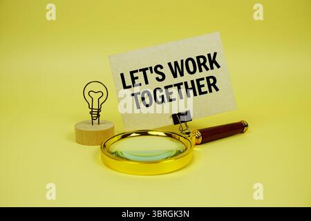 Arbeiten wir gemeinsam eine Textnachricht auf Papierkarte mit Vergrößerungsglas auf gelbem Hintergrund Stockfoto