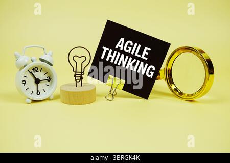 Agile Textnachricht auf Haftnotiz mit Lupe und Wecker auf gelbem Hintergrund Stockfoto