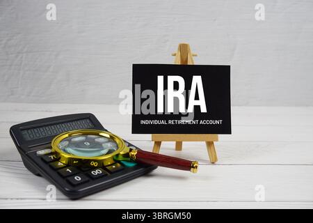 IRA-Abkürzung für individuelle Altersvorsorgekonten mit Lupe und Rechner auf hölzernem Hintergrund Stockfoto