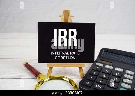 IRR Internal Rate of Return text with magnifying glass and calculator on wooden background. Stockfoto