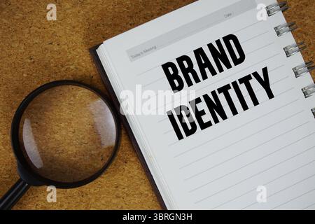 Text der Markenidentität auf Notizbuchpapier mit Lupe geschrieben Stockfoto