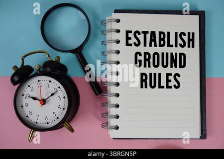 Legen Sie den Text der Ground Rules fest, der auf Notizbuchpapier mit Lupe und Wecker geschrieben ist Stockfoto