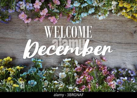 Begrüßungstext im Dezember mit Blumenrahmen auf hölzernem Hintergrund Stockfoto