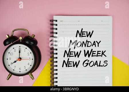 Neuer Montag neue Woche Text der neuen Ziele auf Notizblock mit Wecker auf rosa Hintergrund geschrieben Stockfoto