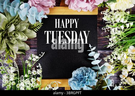 Happy Tuesday Text mit Blumen Blumenstrauß Dekoration auf hölzernem Hintergrund Stockfoto