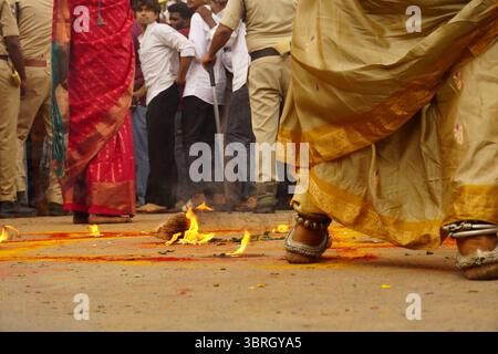 Anhänger, die während des Bonalu-Festivalrituals in Hyderabad, Indien, über das Feuer laufen Stockfoto