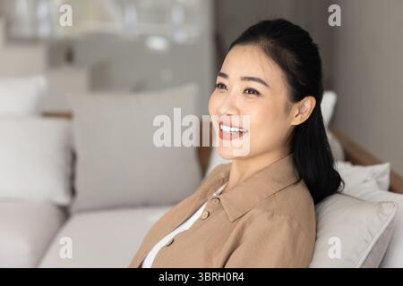 Nahaufnahme einer lächelnden vietnamesischen Frau, die sich allein zu Hause auszieht Stockfoto