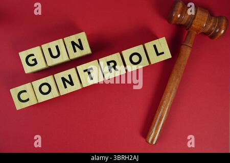 Gun Control Buchstaben mit dem Thema Gesetz, Hammer oder Hammer des Richters liegen auf gelbem Hintergrund Stockfoto