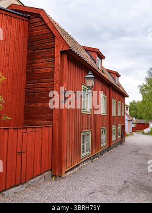 Sodertalje, Schweden - 6. Juni 2025: Ein bezauberndes rotes Holzhaus mit schrägem Dach und grünen Fensterrahmen. Das Gebäude verfügt über eine Laterne und ist surr Stockfoto