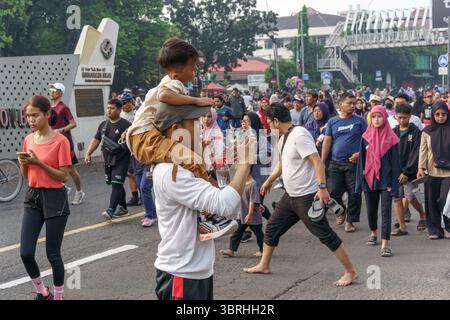 Bekasi, Indonesien, 13. Juli 2025: Ein Vater trägt seinen Sohn auf seinen Schultern in einer glücklichen Menge während des autofreien Tages in Summarecon Bekasi. Stockfoto