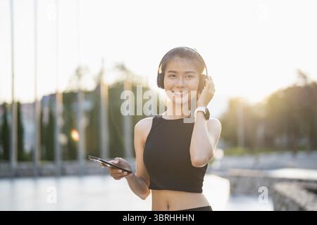 Happy Active Healthy asian Woman hört Musik mit Kopfhörern für geistige Gesundheit Hören von Audio für Laufen Inspiration Stockfoto