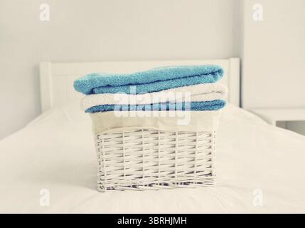 Wäschekorb mit sauberen gefalteten Handtüchern auf dem Bett Stockfoto