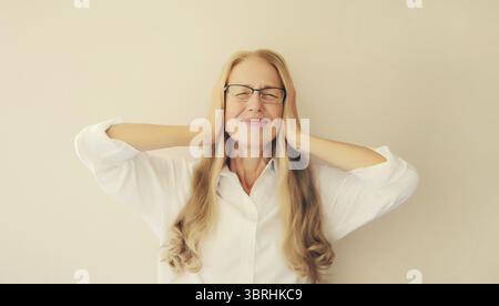 Erschöpfte, müde kaukasische Angestellte mittleren Alters mit Kopfschmerzen oder Schläfenschmerzen, leidet an Migräne, Verspannungen im Kopf zu Hause Stockfoto