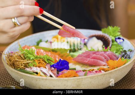 Frau isst köstliches Sashimi, Nahaufnahme auf Essstäbchen Stockfoto