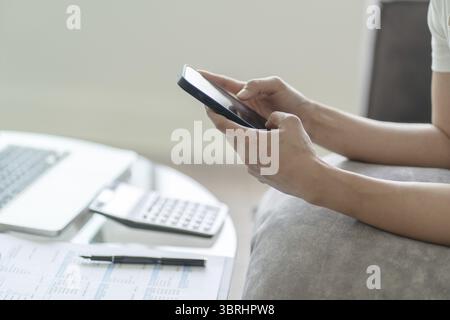 Glückliche schöne asiatische Frau, die Kopfhörer mit Laptop bei der Arbeit trägt oder Musik genießt Stockfoto