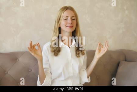 Ruhige entspannte gesunde junge Frau meditiert mit geschlossenen Augen während des Yoga im Zimmer zu Hause Stockfoto