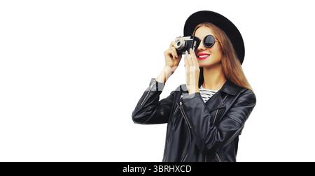 Stilvolles Porträt einer schönen jungen Fotografin, die mit einer Filmkamera fotografiert, mit schwarzem Rundhut, Lederjacke isoliert auf weißem Rücken Stockfoto