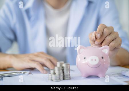 Geld sparen. Geschäftsmann Buchhalter verifizieren wachsende Geschäfte und sparen Geld beim Stapeln von Münzen mit Taschenrechner. Buchhaltungskonzept Stockfoto