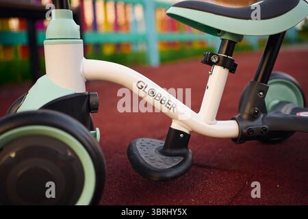 Tyumen, Russland-8. Juli 2025: Balancerad globber parkt bei Tageslicht auf Spielplatzfläche in der Nähe von farbenfrohen Spielstrukturen Stockfoto