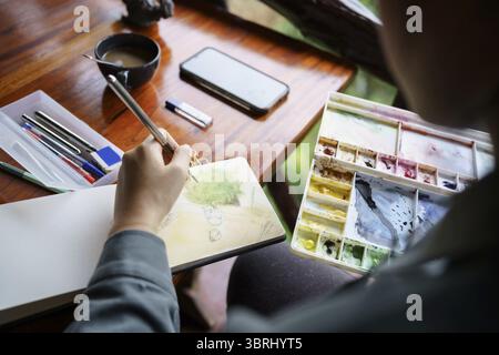 Student im Kunststudio. Hand haltender Künstler Pinsel mischen FarbÖlgemälde auf Palette Kunst Kreativität und Menschen Konzept Stockfoto