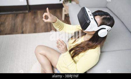 Junge asiatische Frau, die während des VR Experience Future Technology Konzepts virtuelle Realität in Berührung bringt Stockfoto