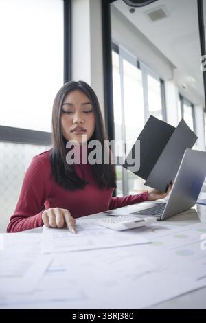 Schöne, selbstbewusste asiatische Geschäftsfrau, die mit Laptophänden arbeitet und Tastatur eingibt. Professioneller Investor, der ein neues Start-up-Projekt durchführt. Geschäftsplan Stockfoto