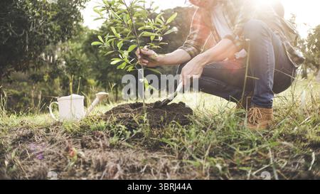 Junger Mann Gärtner, Baum im Garten Pflanzen, Gartenarbeit und Bewässerung von Pflanzen Stockfoto